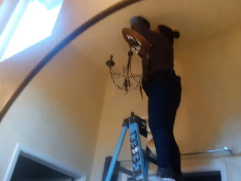 Electrician installing a chandelier in a Sixteen Mile Stand residence